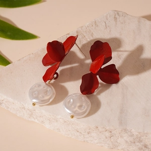 Detail of red flower petal earrings with white freshwater pearl drops on a stone background