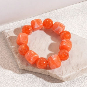Detail of orange and white marble texture acrylic beaded bracelet on stone display