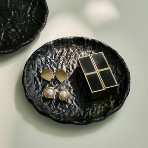 Minimalist gold geometric earrings and pearl studs displayed on a wavy iron tray