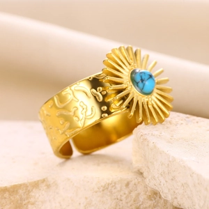 Macro shot of gold sunburst ring with turquoise stone on natural rock texture