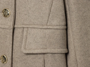 Close-up of khaki wool blend coat featuring golden lion crest embossed buttons and pocket