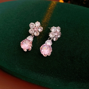 Close-up of pink round-cut gemstone flower earrings on luxury dark green velvet