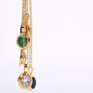 Detail of 18k gold plated necklaces featuring colorful round gemstone pendants on O-chains