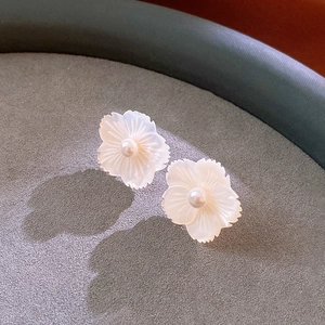 Detailed close-up of shell flower earrings with center pearls on a velvet display tray