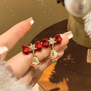 Christmas tree earrings with red bow, snowflake, bell and pearl shown in hand