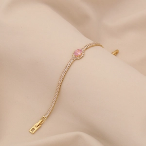 Detailed close-up of a gold bracelet featuring a pink oval gemstone and zircon accents