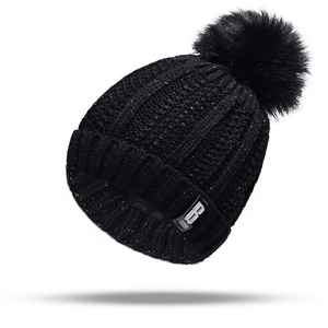 Close-up of black knit beanie with gold metallic thread and fluffy faux fur pom-pom