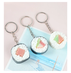 Dettaglio di tre portachiavi sushi giapponesi realistici in PVC su uno sfondo rosa