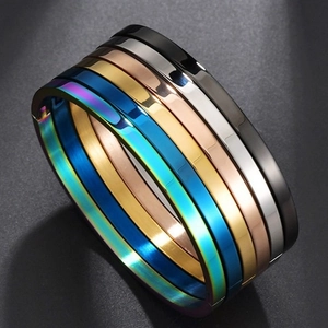 Bracciali rigidi in acciaio inossidabile nero argento e oro impilati in vista frontale