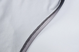 Close-up of high-density stitching and overlock seams on light gray knit athletic fabric