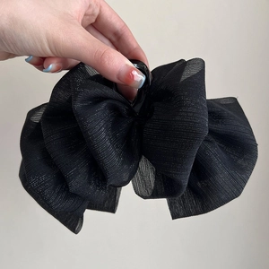 Detailed view of a large black chiffon bow hair claw clip with striped fabric texture
