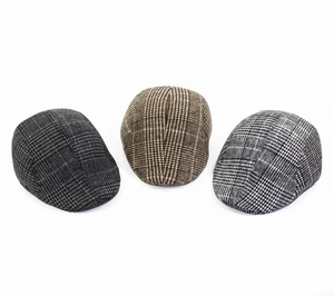 Gros plan de trois casquettes plates vintage à carreaux en gris foncé, marron et gris clair