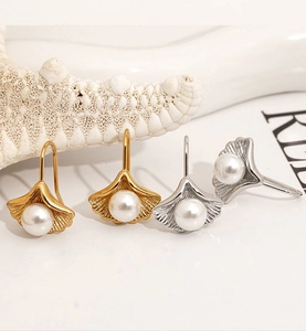 Detailed close-up of shell pearl ginkgo leaf earrings with golden and silver finishes