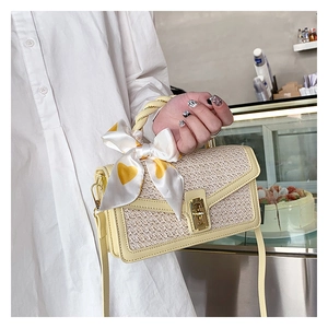 Detail of summer straw handbag featuring a heart pattern silk scarf and golden lock