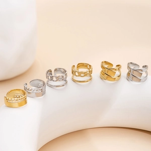 Set of six minimalist gold and silver star pattern ear cuffs on a white curved display