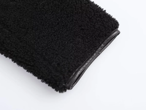 Gros plan sur la texture en fourrure noire et les liserés en cuir de la veste de luxe