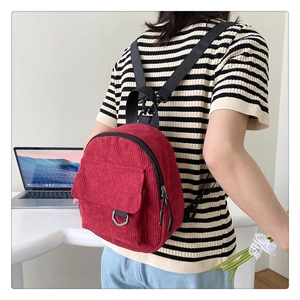 Detailed back view of a red corduroy mini backpack with adjustable black nylon straps
