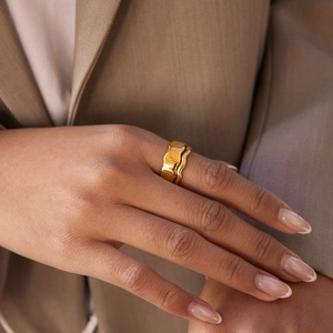Polished 18K gold plated stainless steel irregular wave ring worn with a blazer