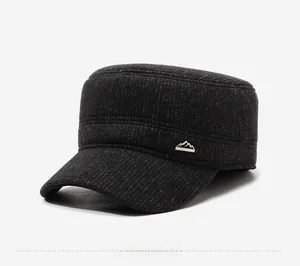 Detail view of winter flat top cap with thick grey fabric and metal mountain logo