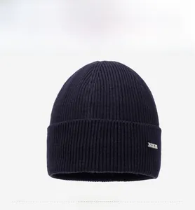 Vue de face d'un bonnet en maille bleu foncé avec un emblème métallique latéral élégant