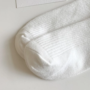 Close-up of white cotton ribbed socks showing fine knitting texture and heel details