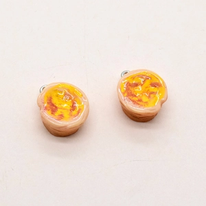 Detail showing a pair of realistic resin egg tart pendants with metal rings for DIY jewelry