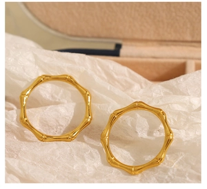 Macro detail of two golden bamboo-shaped geometric stainless steel rings on a white texture