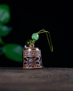 Macro shot of sandalwood sachet pendant with hollow carving and green beads
