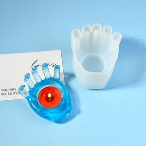 Detailed view of hand-shaped silicone mold with blue resin candle holder and tealight
