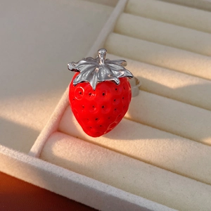 Dettaglio di un anello a fragola in resina rossa con foglie d'argento su vassoio di velluto