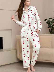 Detailed view of the red heart patterns on the smooth white satin long-sleeved pajama set