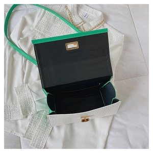 Internal view of white croc-embossed handbag with green strap and gold metal clasp