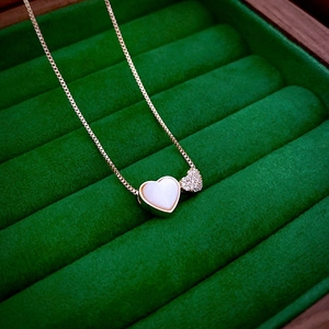 Close-up of gold-plated butterfly heart necklace with zircon in a green velvet box
