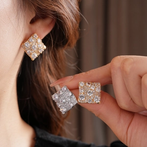 Gros plan de boucles d'oreilles carrées en or et argent avec zircone étincelante
