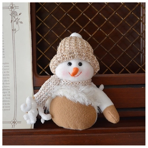 Close-up of a handmade knitted snowman doll with sequined hat and orange carrot nose