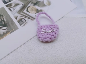 Dettaglio ravvicinato di una mini borsa viola all'uncinetto con scritte in metallo chic