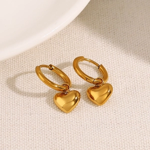 Elegant gold heart drop earrings with polished metallic finish on a white fabric background
