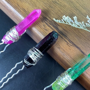 Macro shot of U-shaped hair pins with pink, black, and green natural crystals