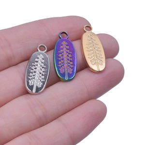 Detailed engraving of pine trees on oval stainless steel pendants in gold and silver