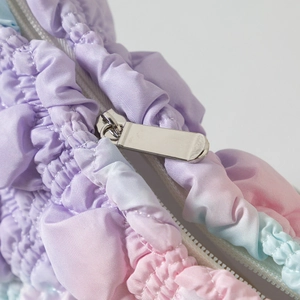 Detail of metal zipper and gradient purple pink blue pleated fabric on cloud makeup bag