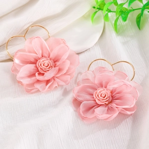 Dettaglio di orecchini a fiore in tessuto rosa con ganci a cuore dorati su bianco