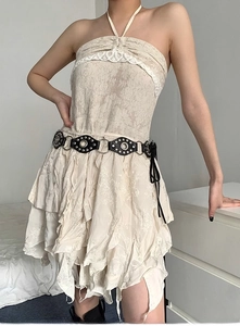 Detail of white halter lace dress featuring a black studded belt with fringe tassel