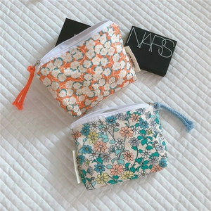 Detail view of two floral cotton mini storage pouches with daisy prints and zipper pulls