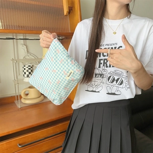 Close-up of blue floral checkered makeup bag with bow print and woven logo detail