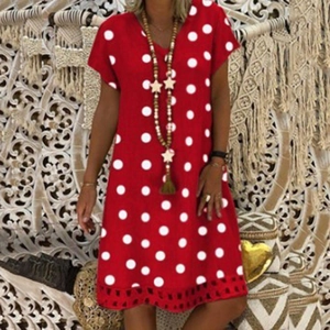 Close-up of red short sleeve V-neck dress with large white polka dots and tassel necklace
