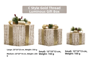 Detail of three lighted Christmas gift boxes with gold ribbons and pine cone accents
