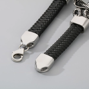 Close-up of black braided leather bracelet featuring a silver snake head metal clasp