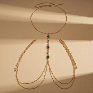 Detail of golden body chain featuring three green oval crystals and tassel design