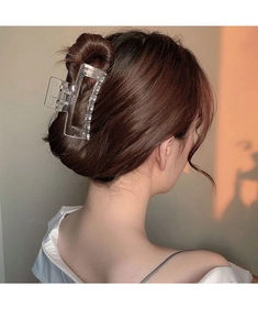 Close-up of a large transparent square hair claw clip styled on a woman's hair bun