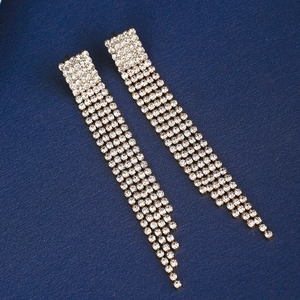 Macro shot of silver tassel earrings featuring shiny cubic zirconia on blue background
